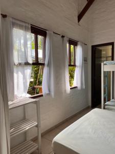 a bedroom with white walls and windows and a bed at Casa Mico Leão Dourado in Bombinhas