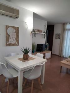 Un comedor con una mesa y sillas blancas. en Cala´n Bosch, en Cala'n Bosch