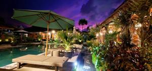 a pool with a table and an umbrella and some plants at Stana Puri Gopa Hotel in Sanur