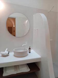 La salle de bains blanche est pourvue d'un lavabo et d'un miroir. dans l'établissement Villa Finika Santorini, à Mesariá