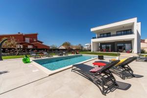 a swimming pool with two chairs and a house at Villa Zen in Vintijan