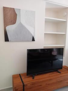 Une télévision à écran plat est installée au-dessus d'une table en bois. dans l'établissement Villa Finika Santorini, à Mesariá