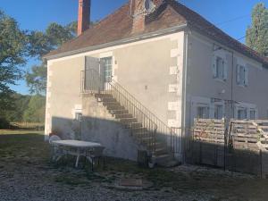 a white building with a table and a staircase at logement indépendant LE POULAILLER proche Guédelon in Treigny