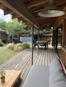 een houten terras met een tafel en een picknicktafel bij Charmant Chalet au bord du lac in Lacanau