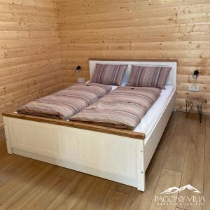 ein großes Bett in einem Zimmer mit Holzwänden in der Unterkunft Pagony Villa in Galyatető