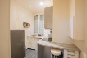 a kitchen with white cabinets and a gray refrigerator at Grand studio de 31 m2 aménagé in Clichy