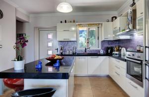 a kitchen with white cabinets and a black counter top at Cozy family home in Katouna in Katouna