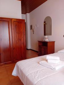 a bedroom with a bed with white sheets and a mirror at Residence Giardino in Montecreto