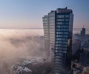 a foggy city with a tall building in the foreground at Hanza Tower Apartament Times Square in Szczecin