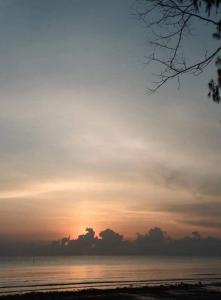 um pôr-do-sol numa praia com o oceano e o céu em บ้านระเบียงเลหลังสวน 1 ห้อง em Ban Hin Sam Kon