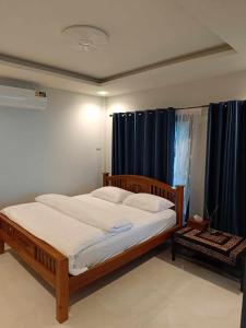 a bedroom with a large bed with blue curtains at บ้านระเบียงเลหลังสวน 1 ห้อง in Ban Hin Sam Kon