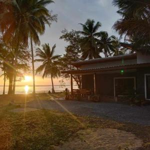 a house on the beach with palm trees and the sunset at บ้านระเบียงเลหลังสวน 1 ห้อง in Ban Hin Sam Kon