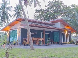 a small house with palm trees in front of it at บ้านระเบียงเลหลังสวน 1 ห้อง in Ban Hin Sam Kon