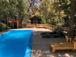 a swimming pool with a bench and a gazebo at Cabañas Kalinaw in Las Trancas