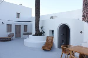 Cette chambre dispose de murs blancs, de chaises et d'une table. dans l'établissement Villa Finika Santorini, à Mesariá