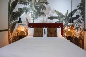 a bedroom with a large bed with plants on the wall at Villa Pruly Hotel Cannes Centre in Cannes