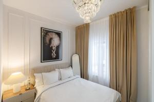a bedroom with a white bed and a chandelier at Luxury and cozy apartment with a beautiful view in Bucharest