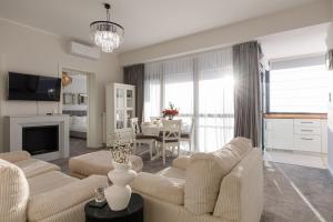 a living room with white furniture and a dining room at Luxury and cozy apartment with a beautiful view in Bucharest