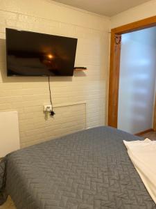 1 dormitorio con 1 cama y TV de pantalla plana en la pared en Alojamiento Sandra - Habitación 02 en Villarrica
