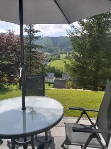una mesa y sillas con una sombrilla en el patio en FeWo Elpetalblick, en Olsberg
