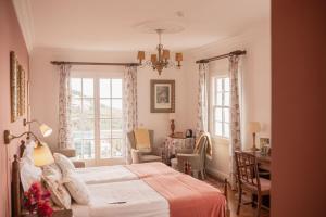 a bedroom with a bed and a desk and windows at Villa Alto Boutique Hotel in Ponta do Sol