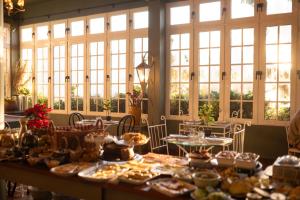 a long table with food on it in a room with windows at Villa Alto Boutique Hotel in Ponta do Sol