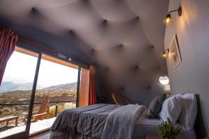 a bedroom with a bed and a large window at Denmoza Eco Lodge in Potrerillos