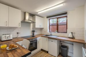 cocina con armarios blancos y encimera de madera en Modern studio flat in Wellington, Telford, en Wellington