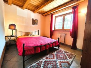 1 dormitorio con 1 cama con edredón rojo y ventana en Hostdomus - Chalet Sciatori Loft, en Pragelato
