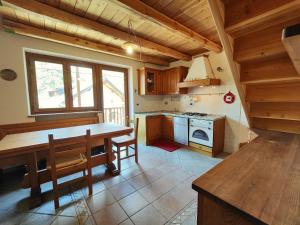 cocina con mesa de madera y fogones en Hostdomus - Chalet Sciatori Loft, en Pragelato