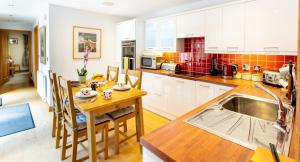 a kitchen with white cabinets and a wooden table at Heads Nook Hall Cottage in Carlisle