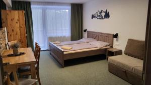 a bedroom with a bed and a table and a chair at Apartmány Nízke Tatry - Krpáčovo in Dolná Lehota +32 photos