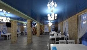 a dining room with tables and a television and chandeliers at Готель Міленіум in Dragobrat