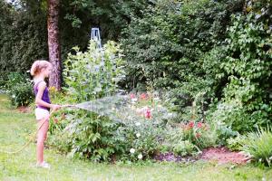 una niña regando un jardín con una manguera en Villa Pranter, en Sillian