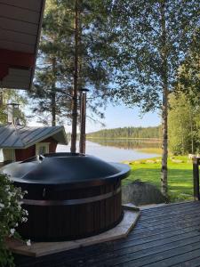 uma banheira de hidromassagem num deque ao lado de um lago em Villa Kuusiranta em Ahtari