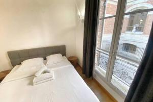 a white bed in a room with a large window at 103 - Studio jardins de plantes Paris 5 in Paris