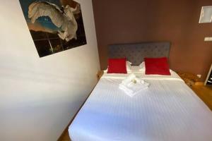 sypialnia z łóżkiem z białą pościelą i czerwonymi poduszkami w obiekcie 105 - Studio Cosy avec Vue sur le Jardin des Plantes w Paryżu