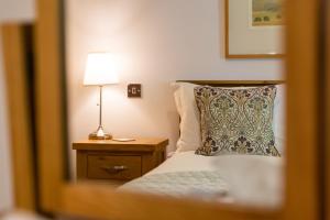 Dormitorio con cama con almohada y lámpara en Heads Nook Hall Cottage en Carlisle