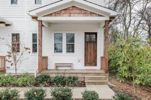 una casa blanca con un banco en el porche delantero en The Porter - East Nash Lively Comfort, Dog-Friendly, en Nashville