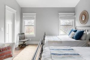a bedroom with two beds and a chair and two windows at The Porter - East Nash Lively Comfort, Dog-Friendly in Nashville