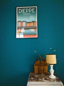 une photo sur un mur bleu avec une table et une lampe dans l'établissement Les Vitraux de Saint Rémi, à Dieppe