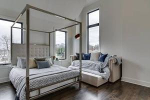 a bedroom with a four poster bed and windows at The Kora - Stylish Rooftop Retreat in Gulch in Nashville