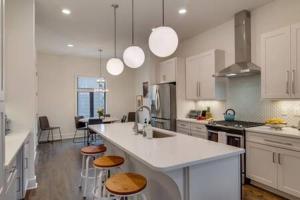 a kitchen with white cabinets and a large island with bar stools at The Kora - Stylish Rooftop Retreat in Gulch in Nashville