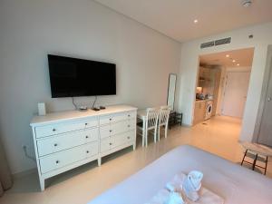 a living room with a white dresser with a flat screen tv at Black and white flower oasis in Seven Palm in Dubai