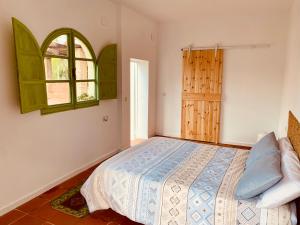 a bedroom with a bed and an open window at La Casita del Cactus - Casa de campo con piscina in Alcalá de Guadaira