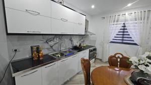 een keuken met witte kasten, een tafel en een wastafel bij Guesthouse Albi in Berat