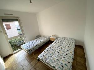 two beds in a room with a window at Bel appartement proche des criques - Climatisé in Six-Fours-les-Plages