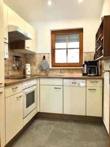 a large kitchen with white cabinets and a window at Ferienwohnung Enzian 3 im Feriendorf Sonnenhang im Allgäu in Missen-Wilhams +63 photos