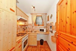 een keuken met houten kasten, een wastafel en een magnetron bij Ferienwohnung Enzian 2 im Feriendorf Sonnenhang im Allgäu in Missen-Wilhams