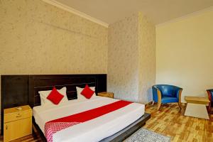 a bedroom with a bed and a blue chair at OYO Flagship Hotel Jagdambey Residency in Noida